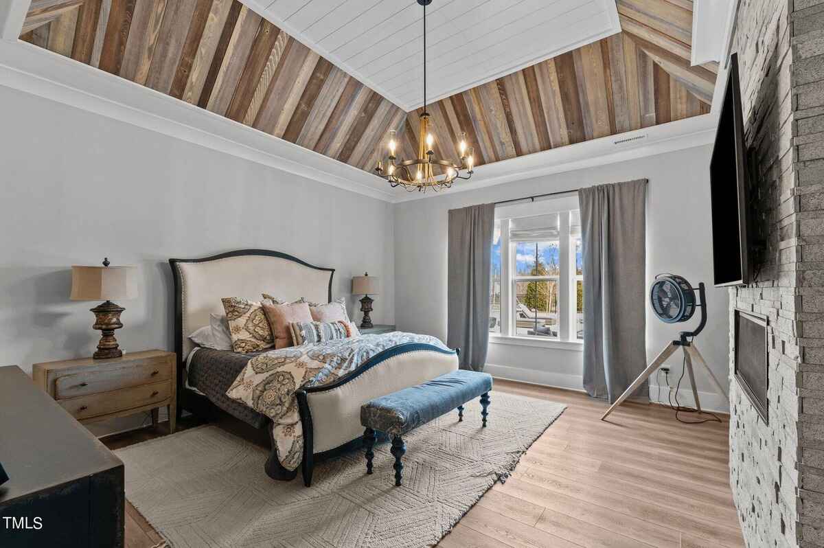 Bedroom with vaulted ceiling, rustic wood accents, and a large window.