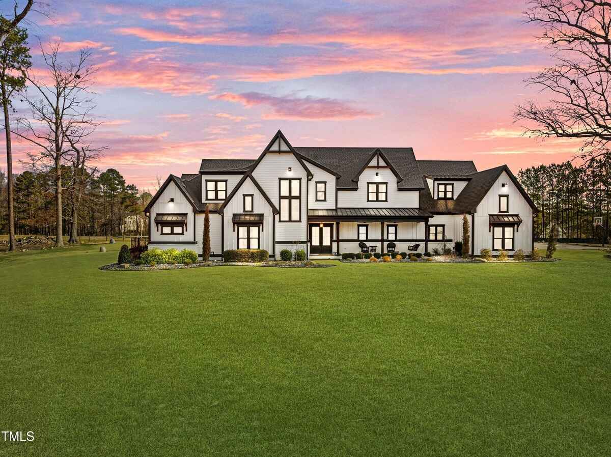 Modern farmhouse-style exterior featuring white siding, black accents, and large green lawn.