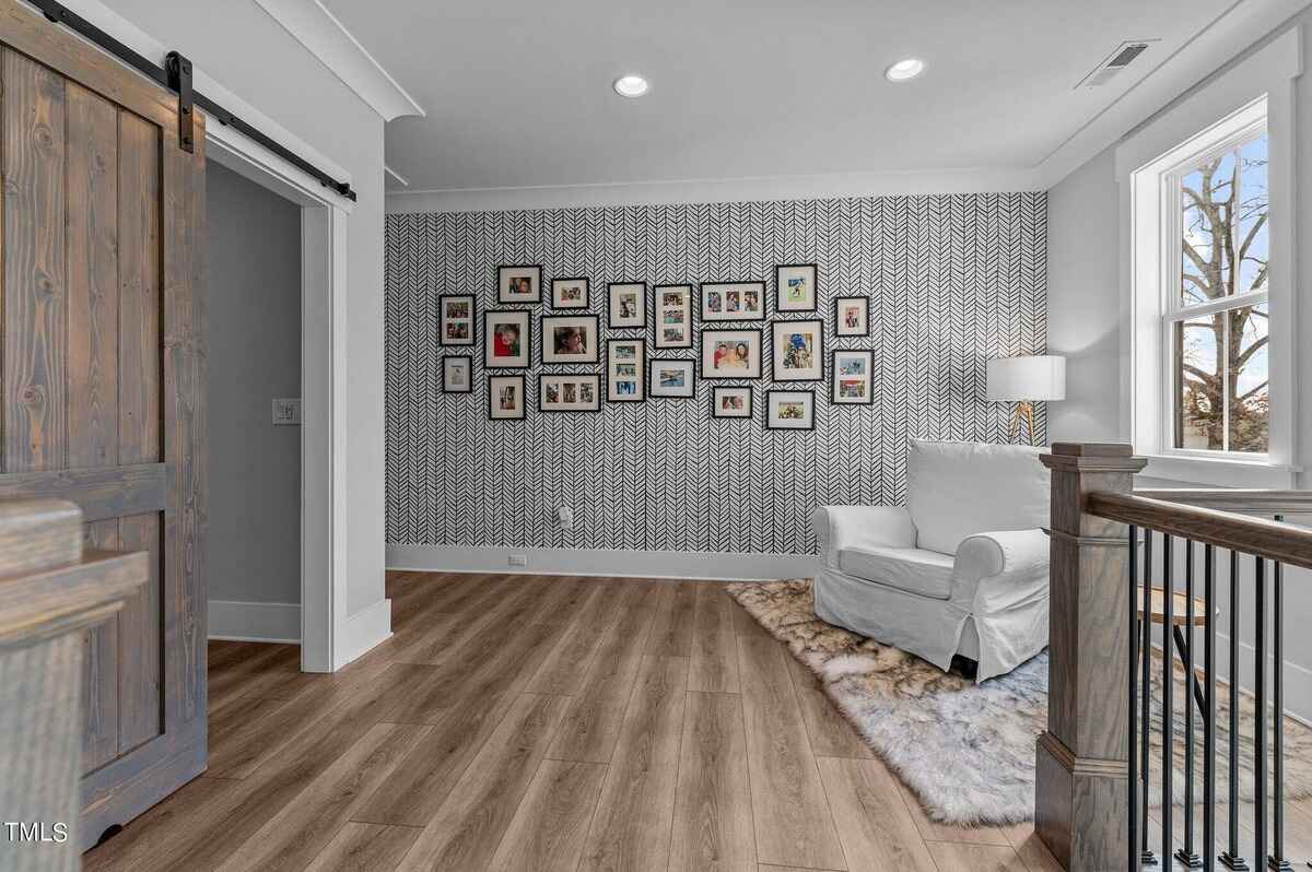 Cozy reading nook with a gallery wall of framed photos beside a large window.