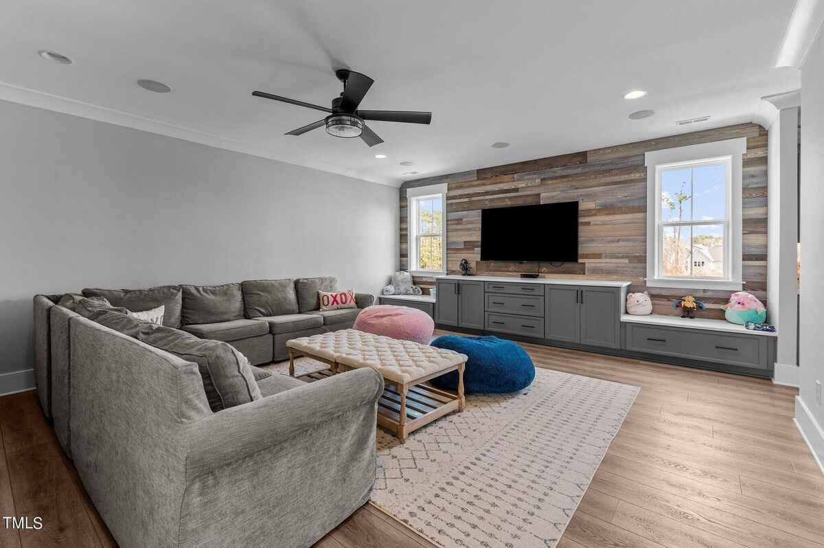 Spacious living room with a sectional sofa, accent chairs, and a wooden feature wall with a mounted TV.