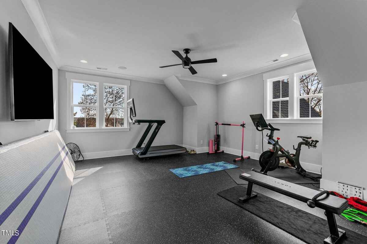 Well-equipped gym space featuring exercise equipment and a mounted TV.