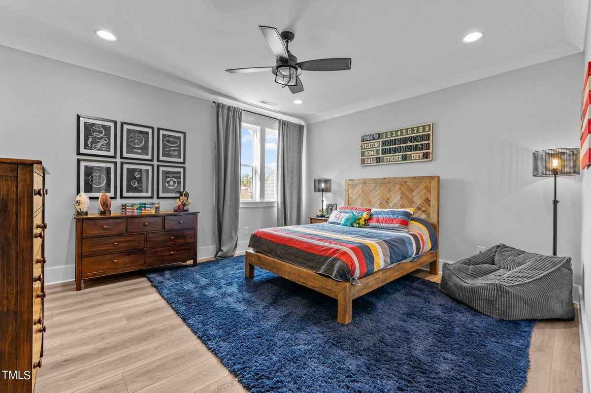 Contemporary bedroom featuring a bold blue rug, a rustic bedframe, and sports-themed wall art.