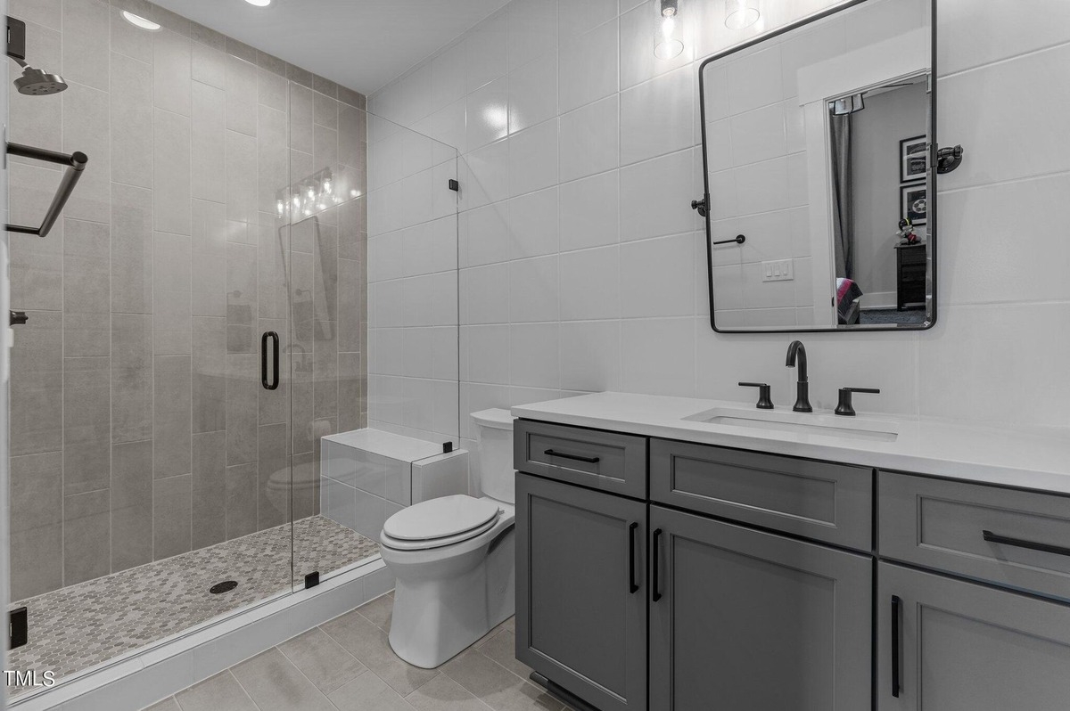 Sleek bathroom with a glass-enclosed shower, dual sinks, and modern fixtures.