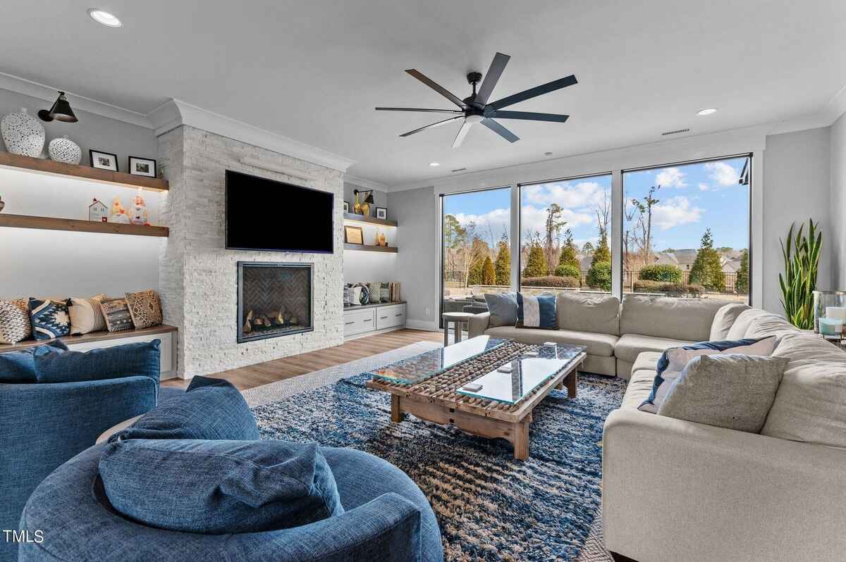 Spacious living room with fireplace, built-in shelving, and wall of large windows.