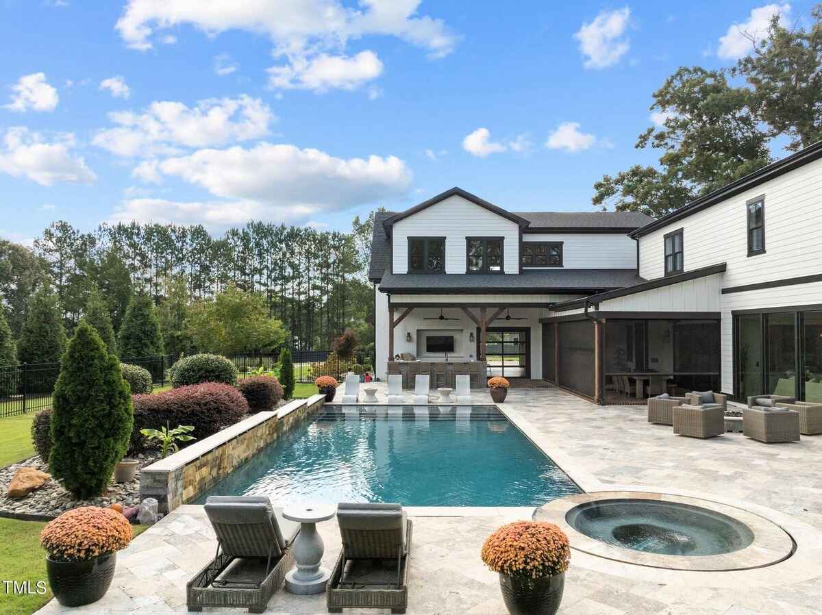 Backyard area showcasing a luxurious swimming pool, patio seating, and manicured landscaping.