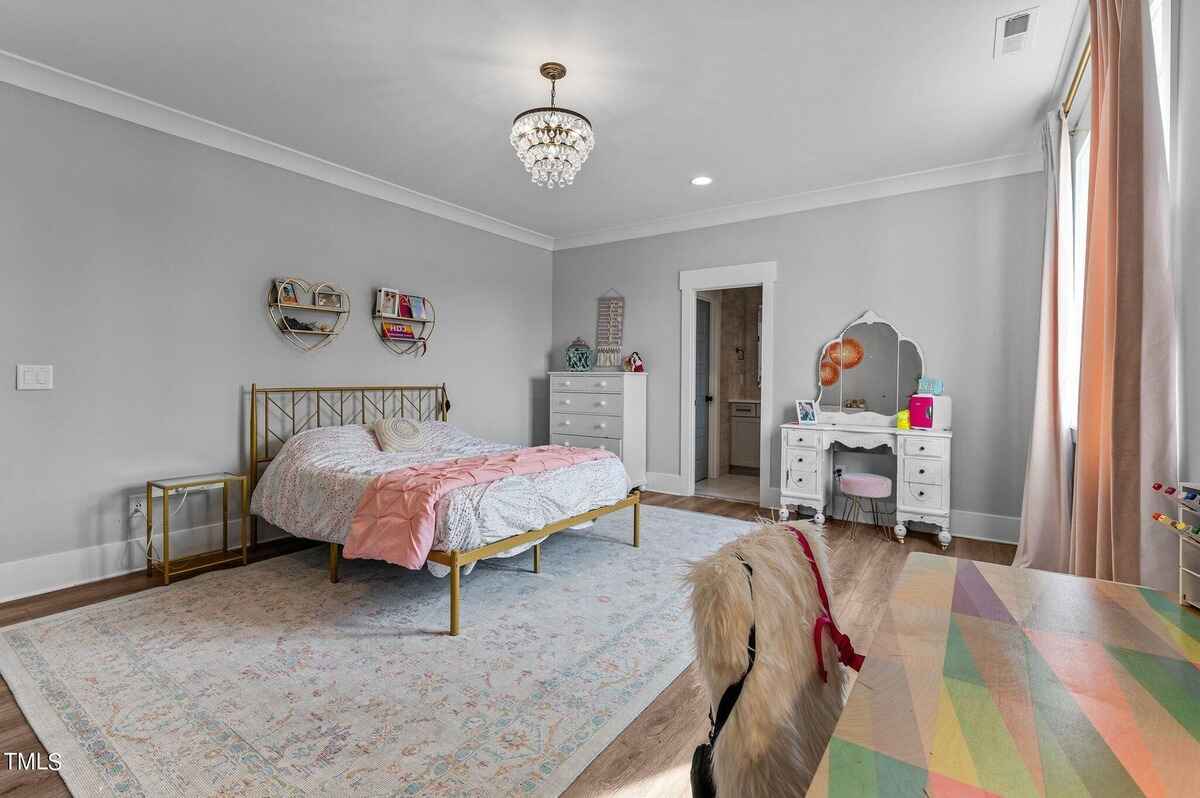 Bedroom features a gold metal bed frame, pink bedding, a vanity, and a colorful desk.