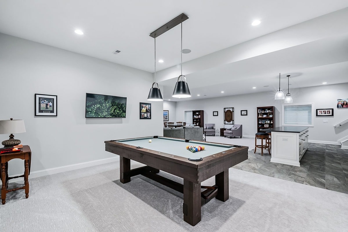 This open-concept basement space, bathed in natural light, showcases a seamless flow between the living room and kitchen. 