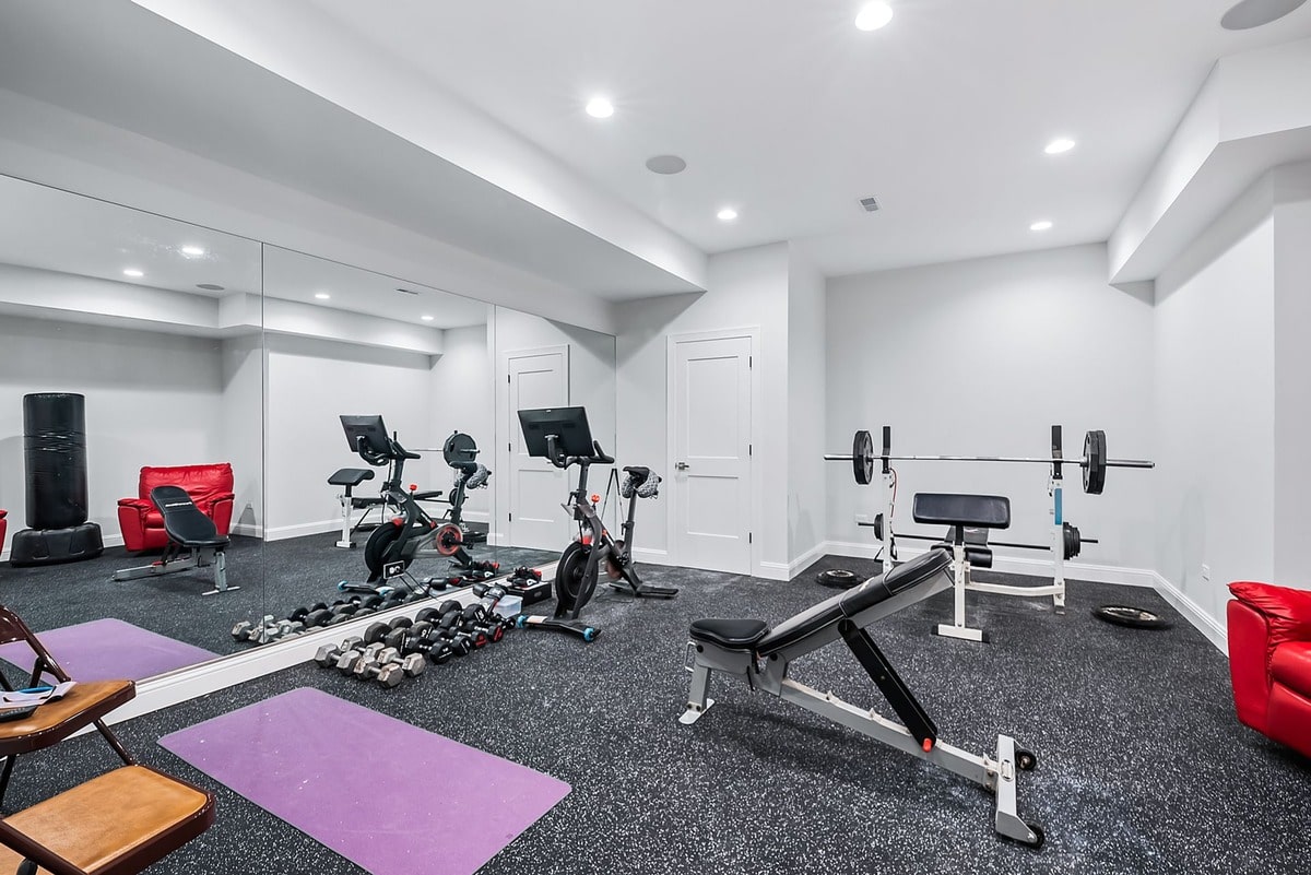 This expansive basement gym, captured from a wide-angle perspective, exudes an air of sophisticated elegance.