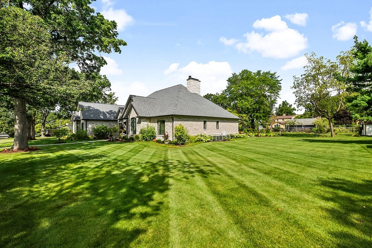 A side view reveals the home's expansive backyard, where a generously sized porch beckons with a cozy seating area and inviting fireplace.