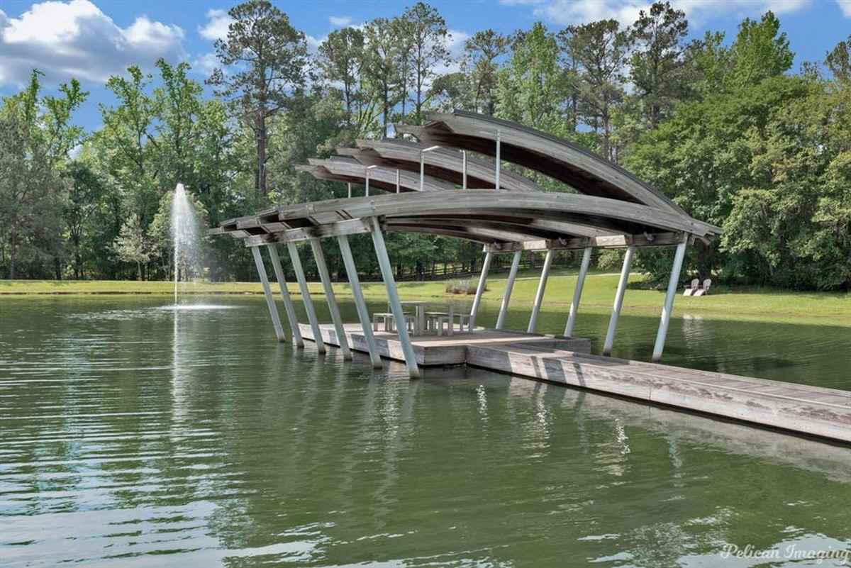 A wooden dock with a unique cover extending into a tranquil private pond.