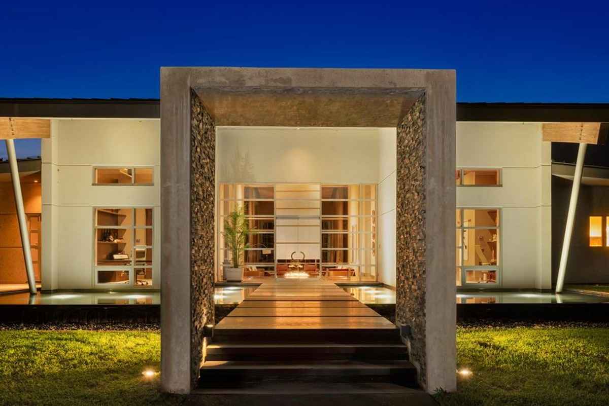 A beautifully lit modern entrance framed by a concrete structure at dusk.