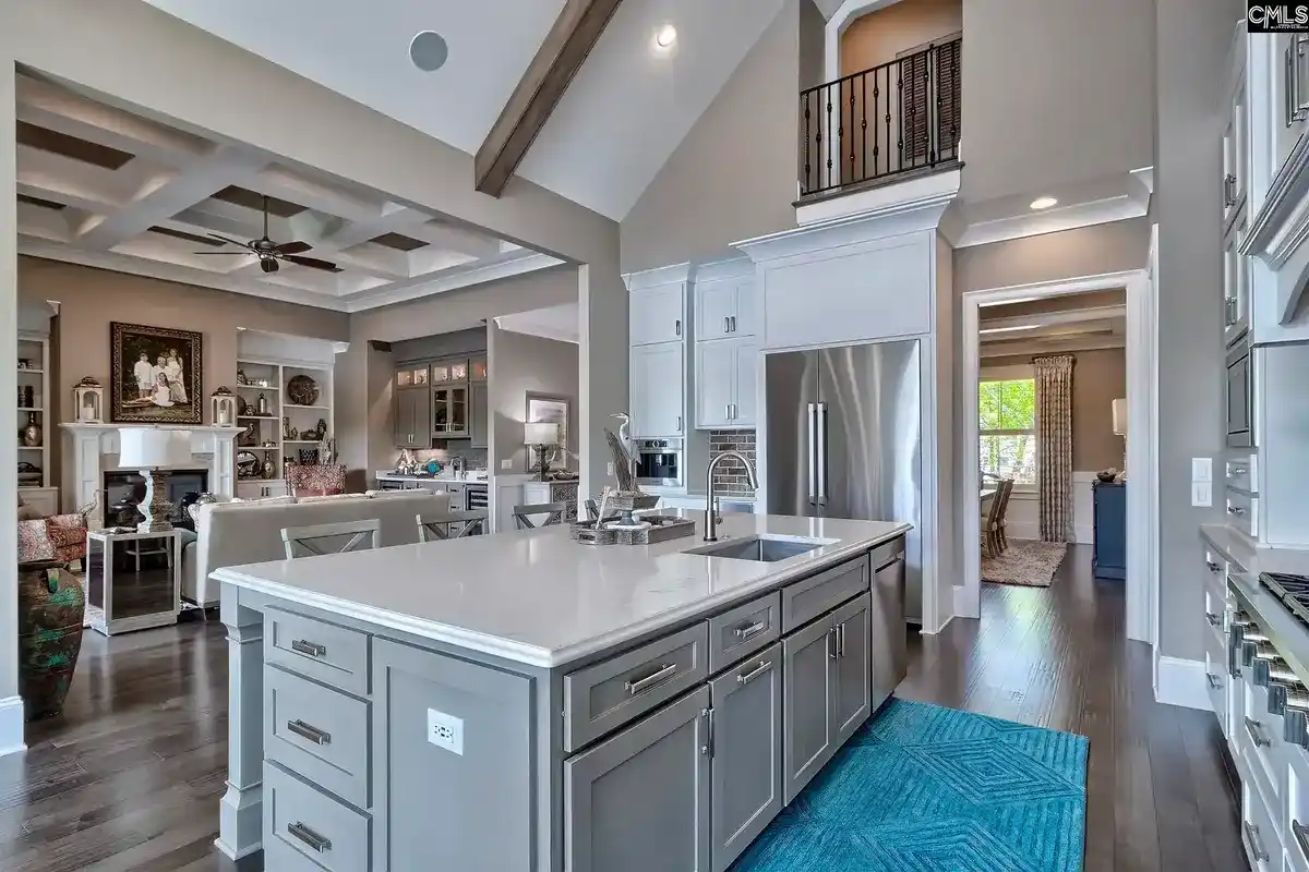 A spacious kitchen with a large island and stainless steel appliances opens to a living area with high ceilings and a loft.