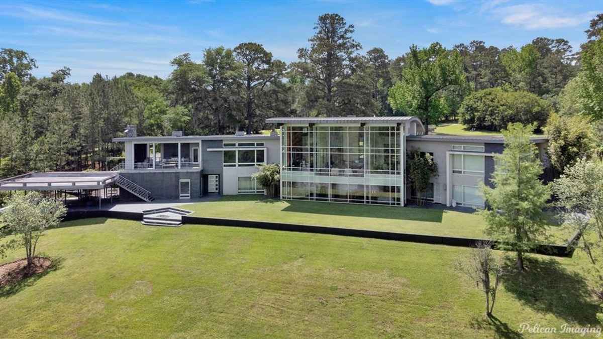 The full rear facade of the house showcasing glass walls and an expansive lawn.