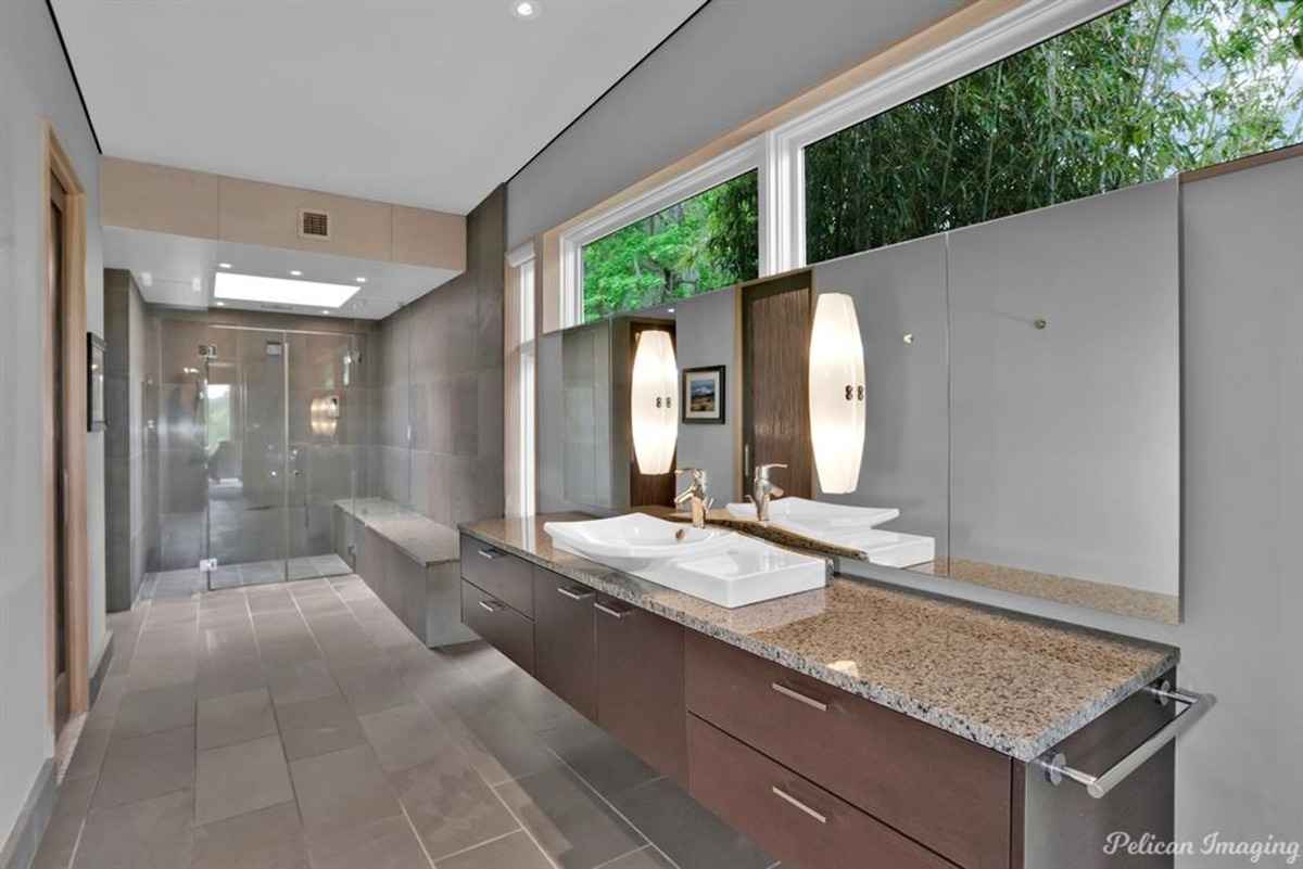 A spacious bathroom with dual sinks, a large mirror, and a walk-in shower.