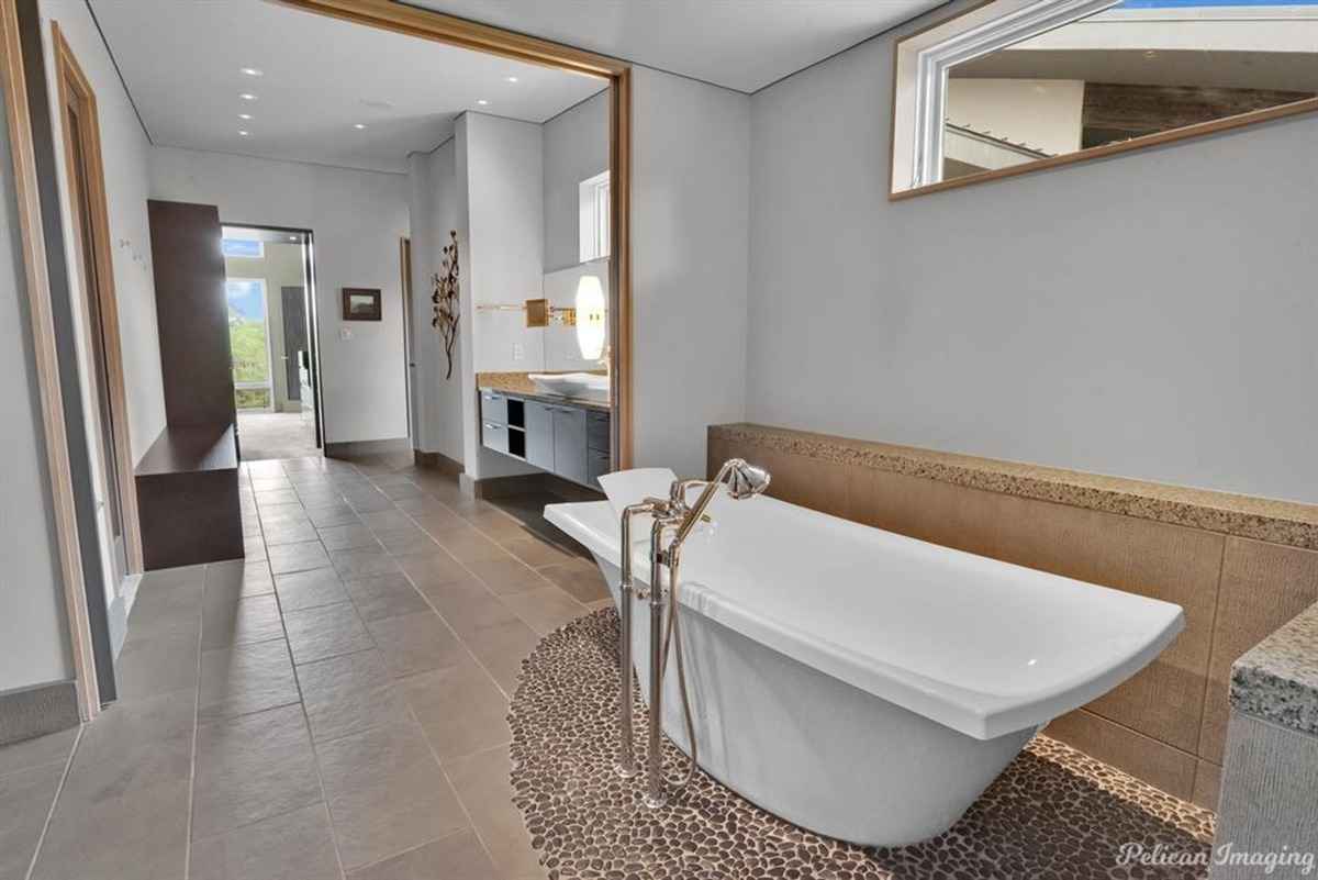 A luxurious bathroom featuring a freestanding tub, pebble accents, and a spacious layout.