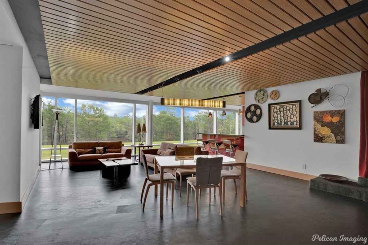 A multi-functional space with seating, a dining area, and large windows for natural light.