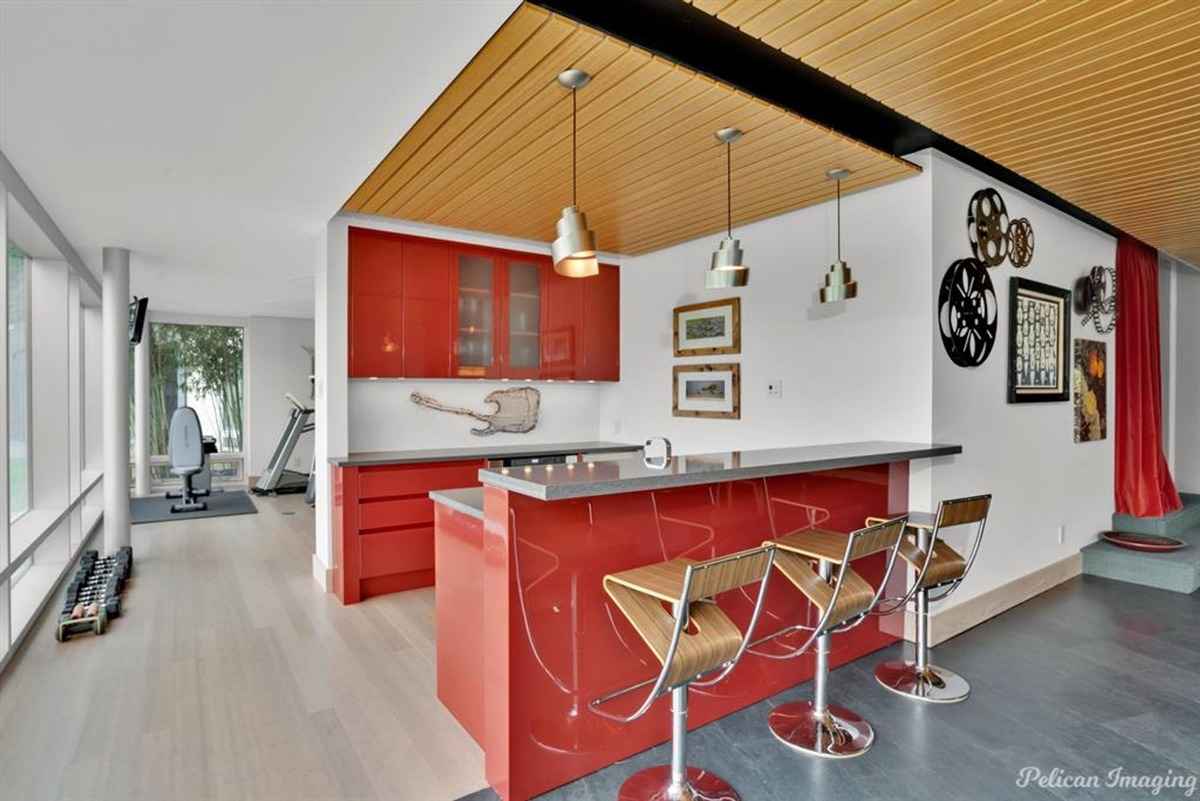 A vibrant red home bar with pendant lighting and a modern design.