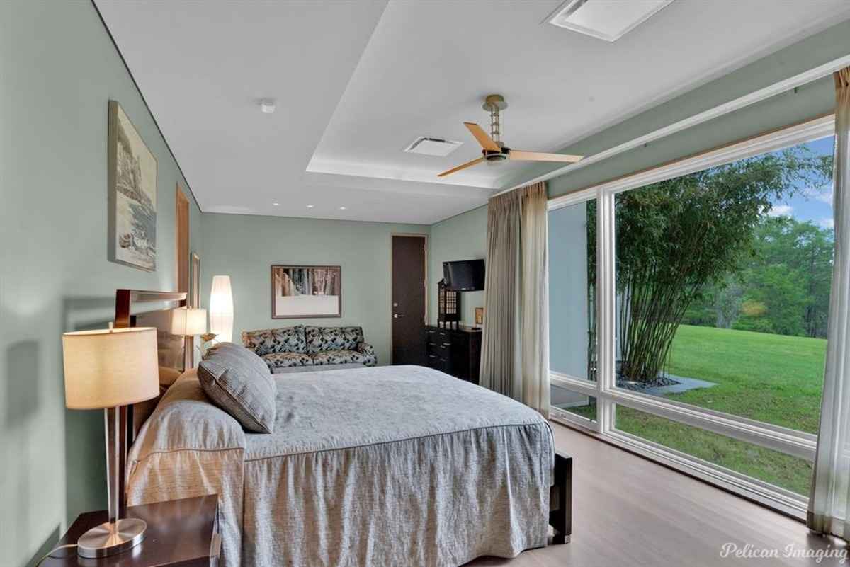  A cozy bedroom with large windows offering a serene view of the greenery outside.