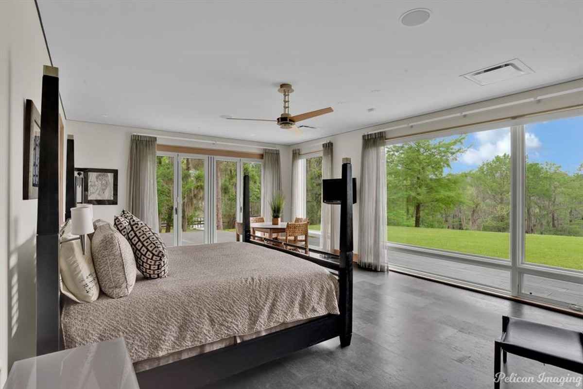  A modern bedroom with large windows and doors leading to a lush outdoor area.