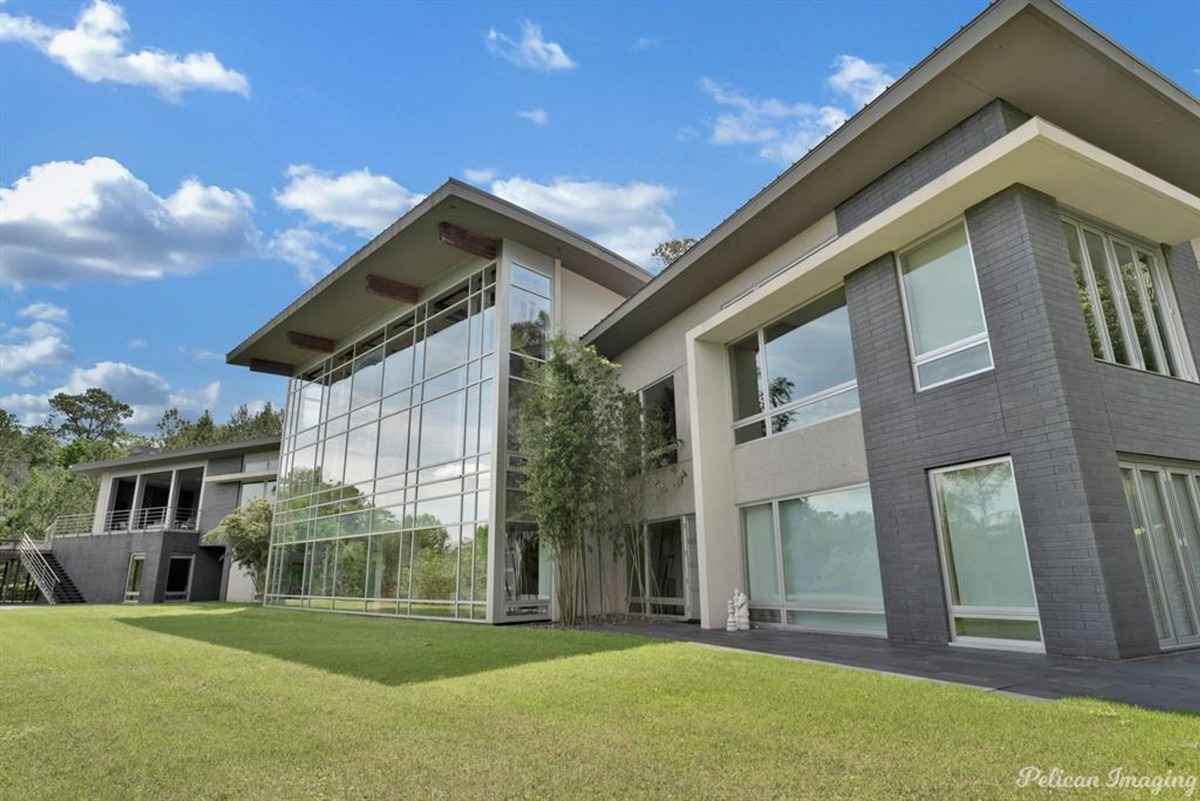 A contemporary home with expansive glass windows and a neatly manicured lawn.