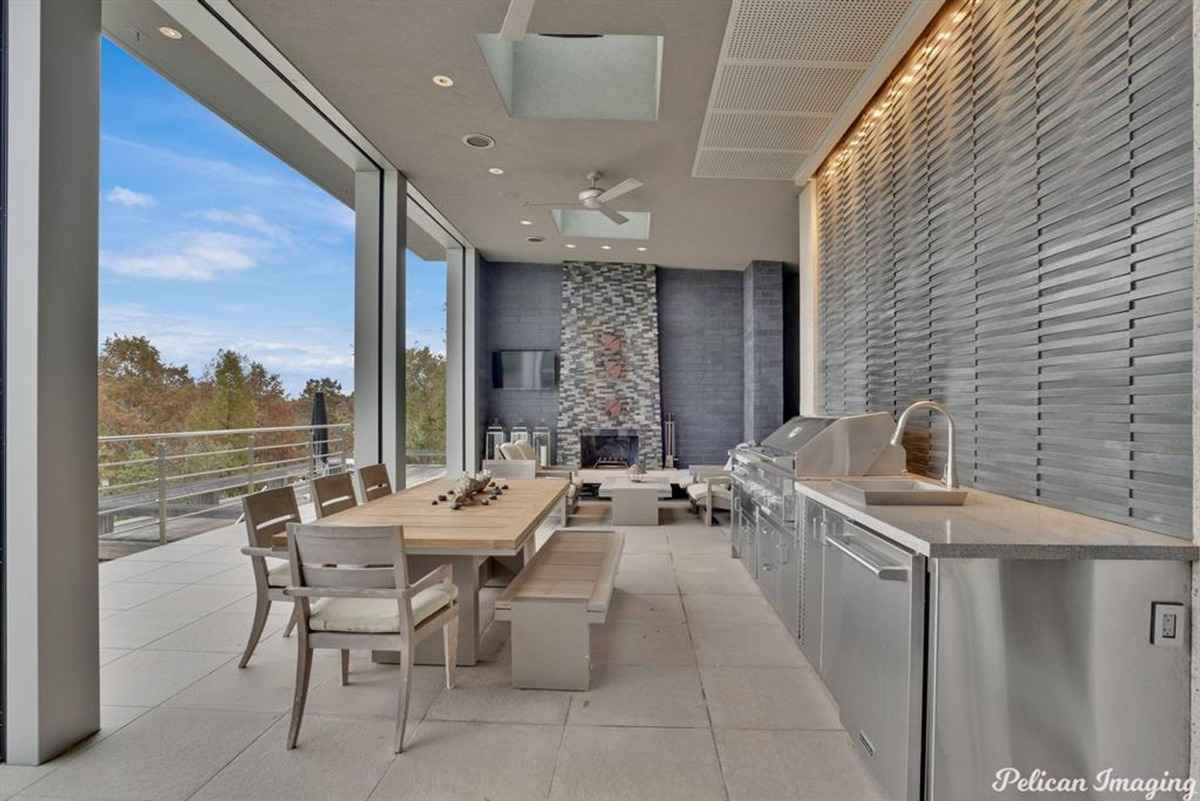 A covered patio with a dining area, built-in grill, and a cozy fireplace.