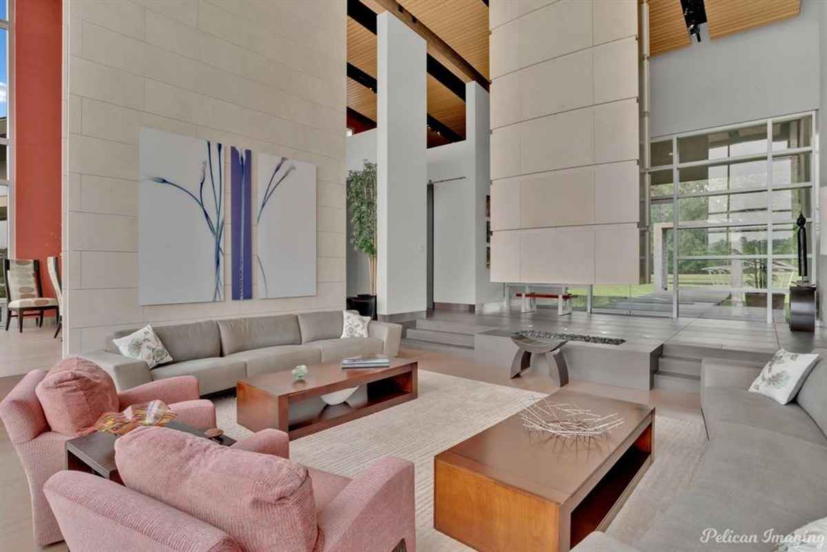 A stylish living area with high ceilings, contemporary furniture, and large windows.