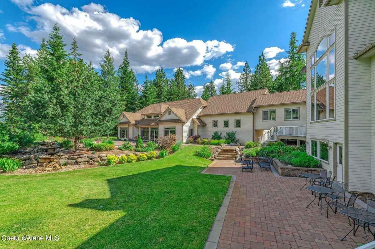 A large house with a patio and landscaping is shown. There are trees and a grassy area in the background.