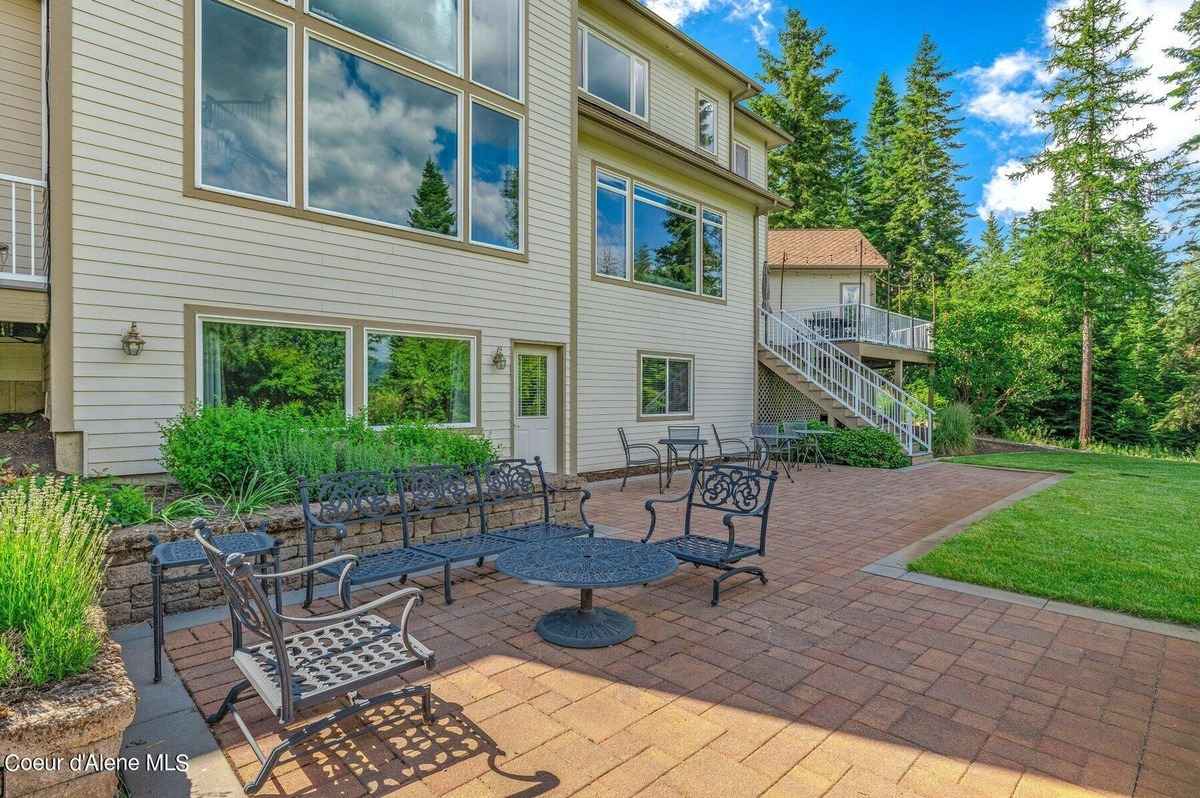 A patio with furniture is shown next to a house. There are trees and grass in the background.