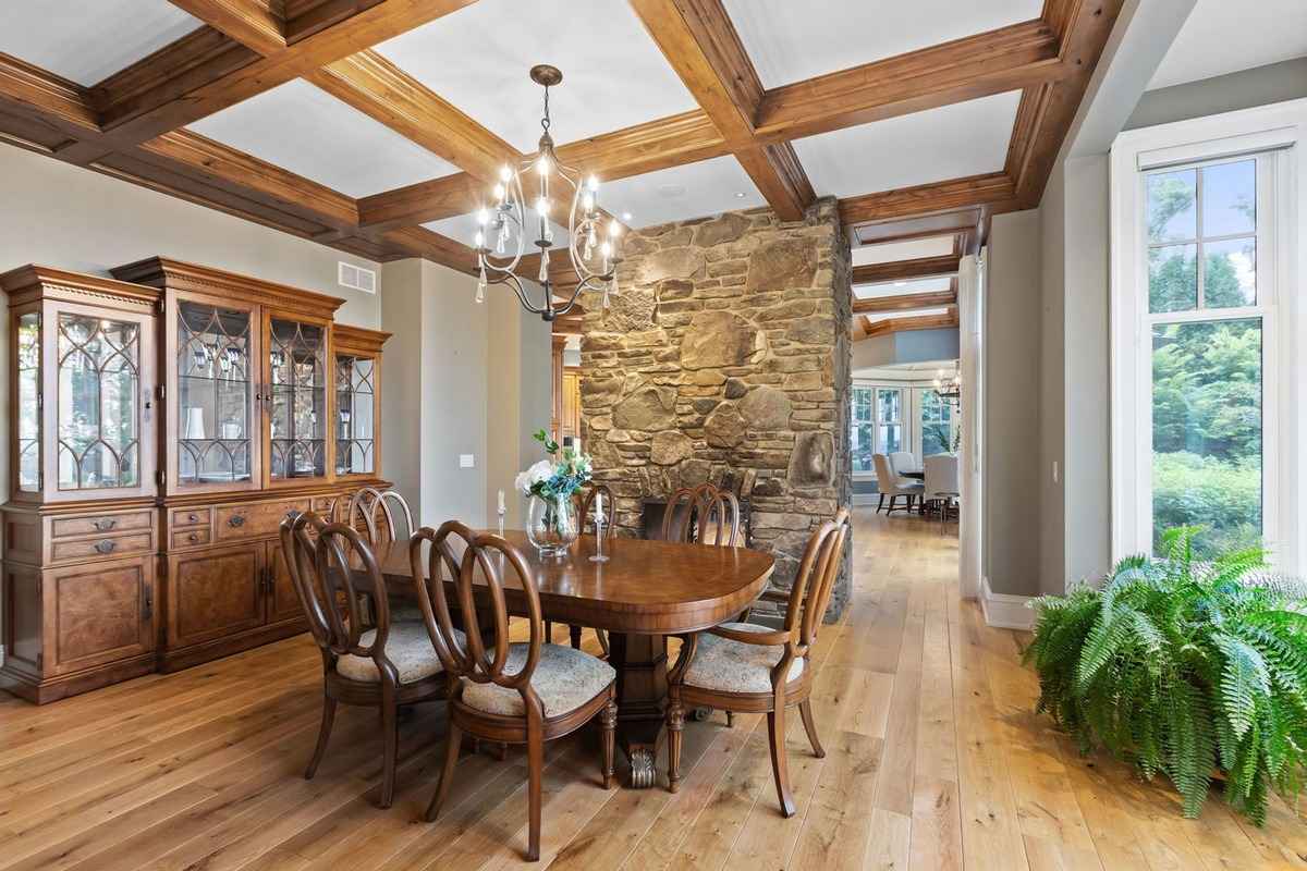 A formal dining room featuring a stone accent wall, a chandelier, and classic wooden furniture.