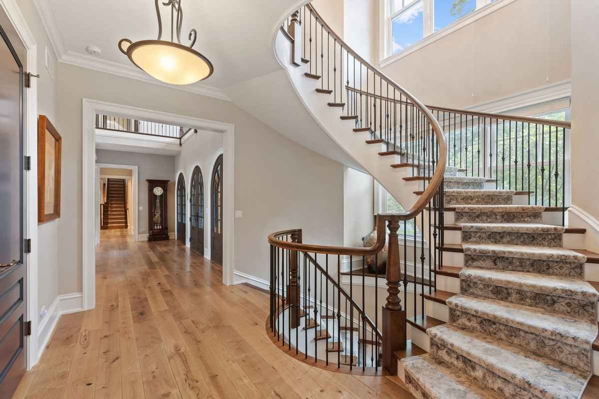 A sweeping staircase with wrought iron railing, leading to a brightly lit upper landing.