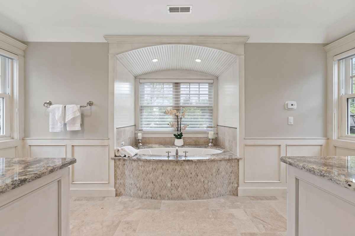 A spacious bathroom with a central soaking tub, granite accents, and soft lighting.