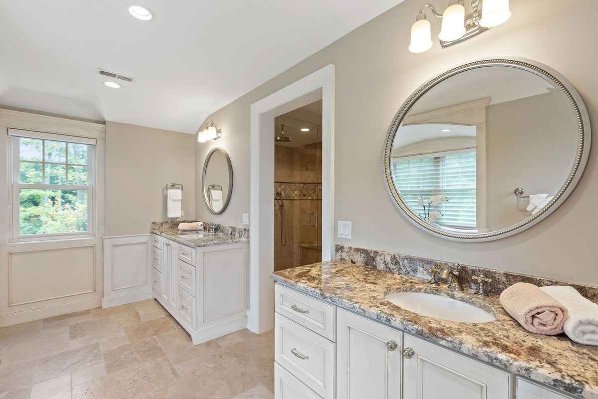 A spacious bathroom featuring dual vanities and elegant granite surfaces.