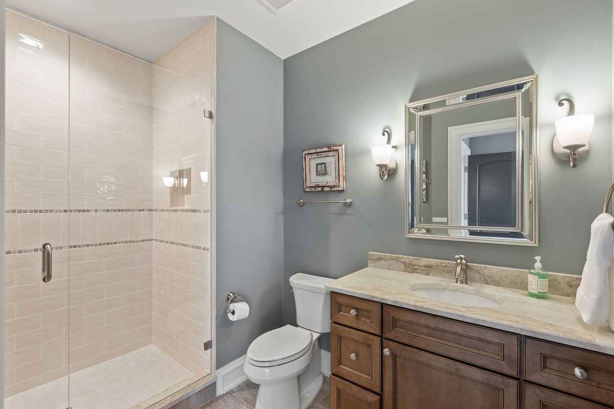 A stylish bathroom with a glass-enclosed shower and wood cabinetry.