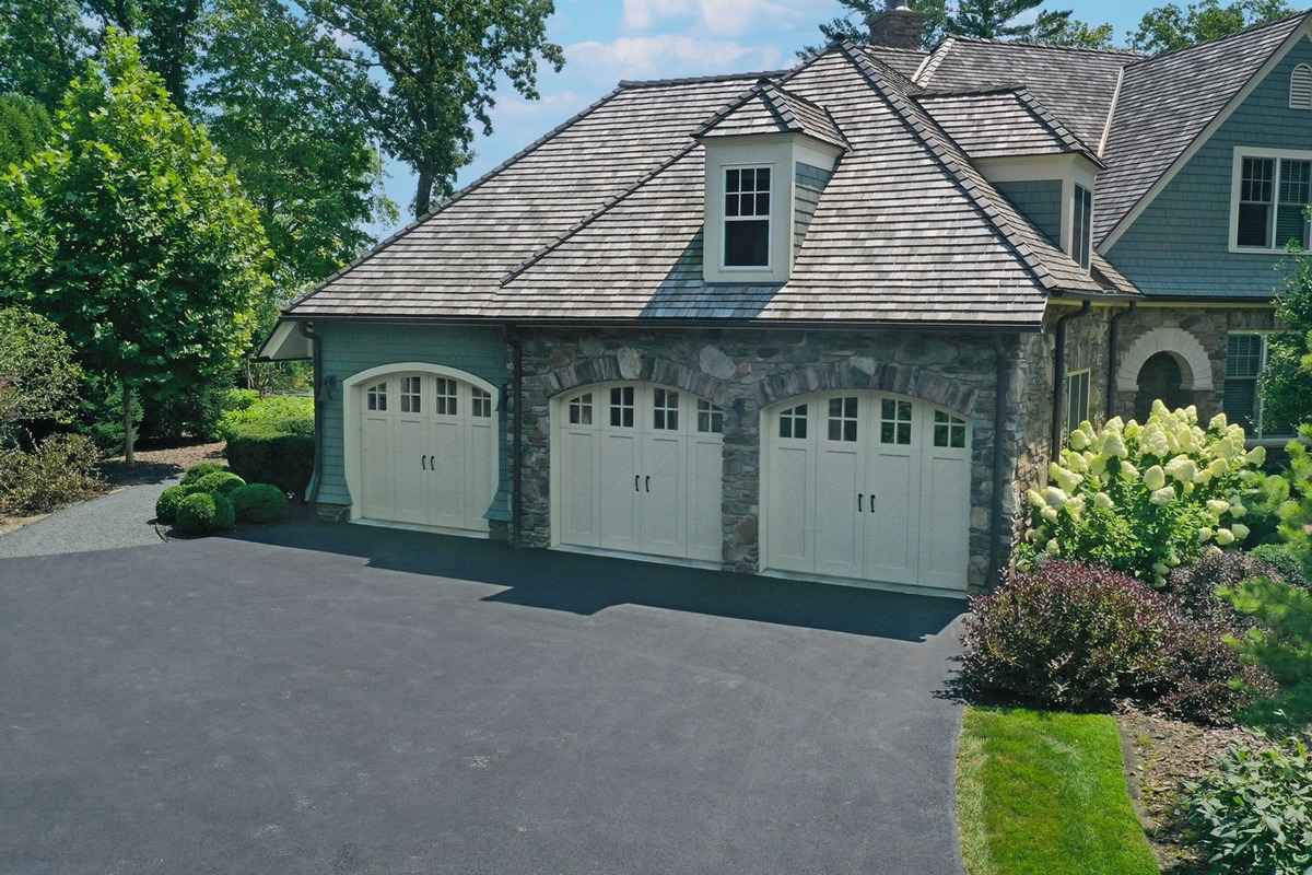 An elegant garage exterior with stone accents and three arched doors.