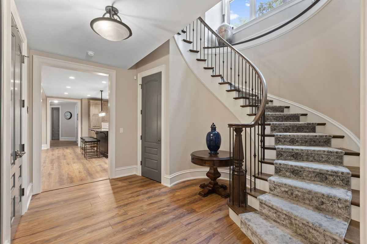 A bright lower-level hallway with a spiral staircase and access to the kitchen and living areas.