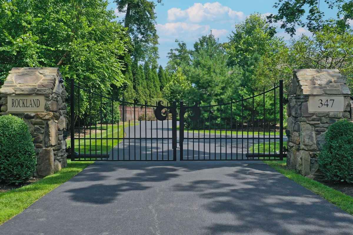 A gated entrance with stone pillars, marked "Rockland" and "347," leading to a tree-lined driveway.