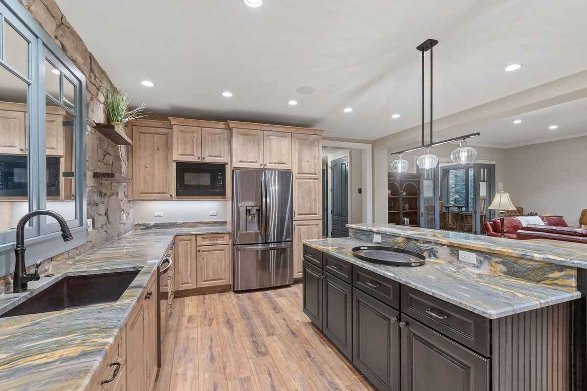 A modern kitchenette with stone countertops, wooden cabinetry, and a polished design.