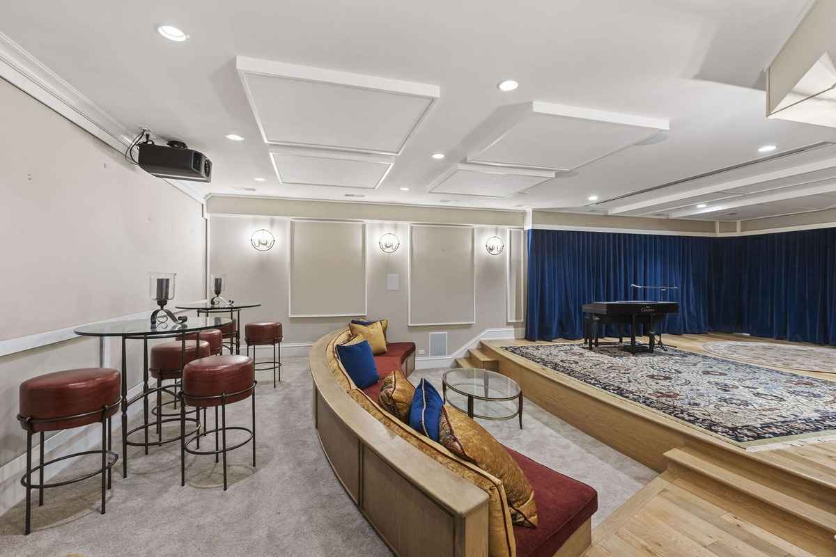 An elegant home theater with cozy seating, a stage, and acoustic panels.