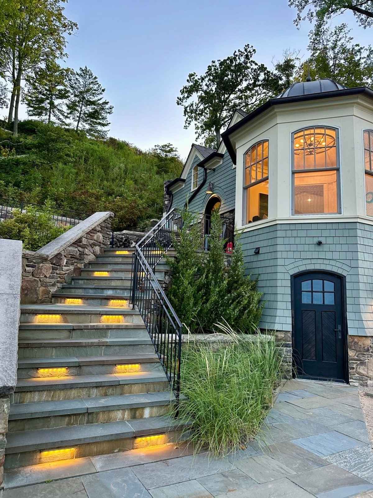 A beautifully lit stone staircase leading to a charming lakeside cottage.