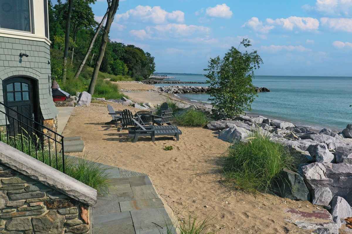 A sandy beach area with lounge chairs overlooking the calm waters and rock formations.