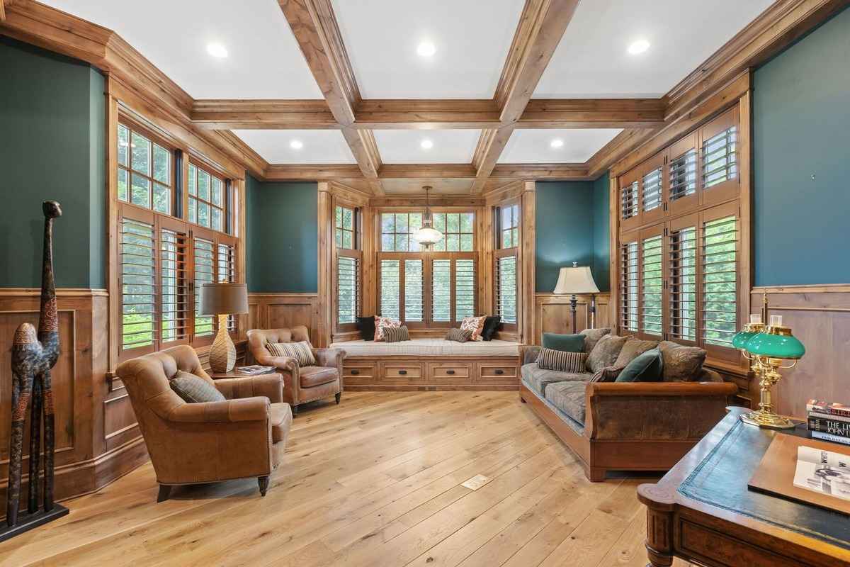 A cozy sitting room with rich wooden paneling, built-in window seating, and warm lighting.