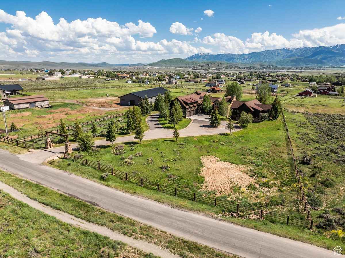 Aerial view of a ranch-style property with wide open fields and mountains in the background.