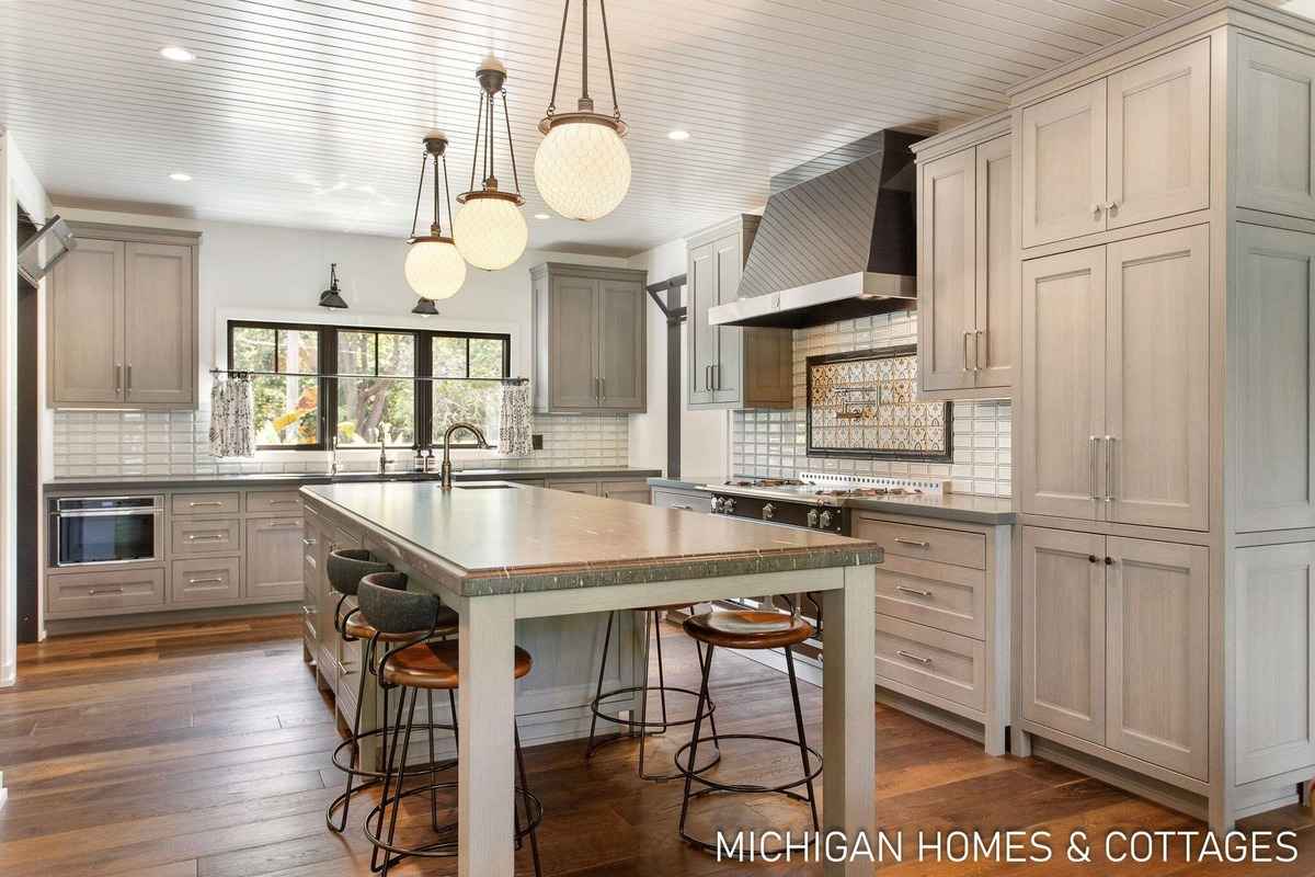 A bright kitchen features light-colored cabinetry, a large island with bar stools, and pendant lighting.