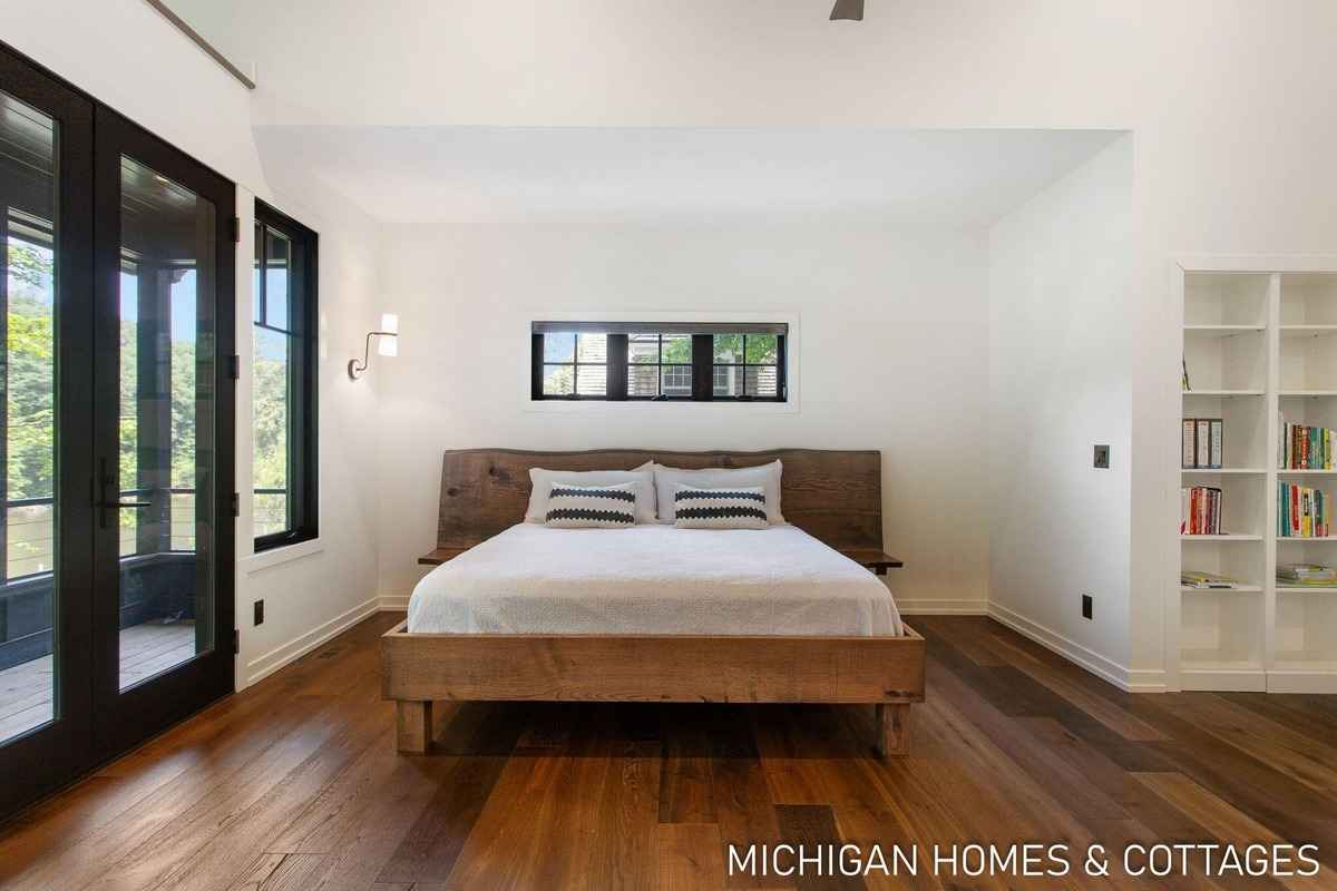 A bedroom features a rustic wooden bed, hardwood floors, and a built-in bookcase.