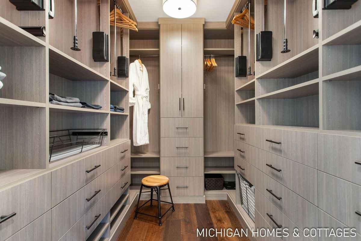 A large walk-in closet with light-colored wood shelving and drawers is shown.