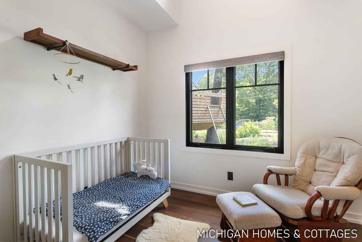 A nursery with a crib, a rocking chair, and a window showing a treehouse is shown.