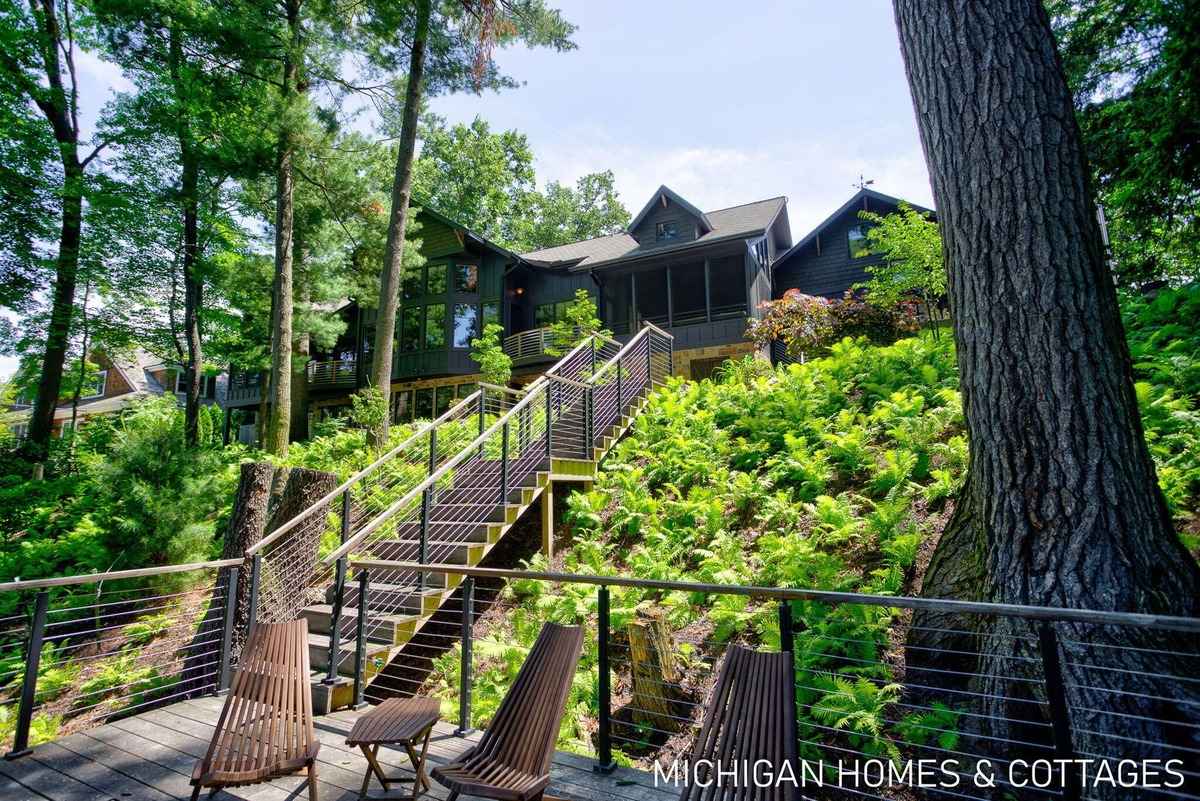 A large house on a hillside with stairs leading down to a deck is shown.