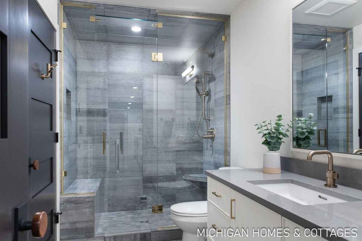 A bathroom with a glass-enclosed shower, a built-in bench, and a modern vanity is shown.