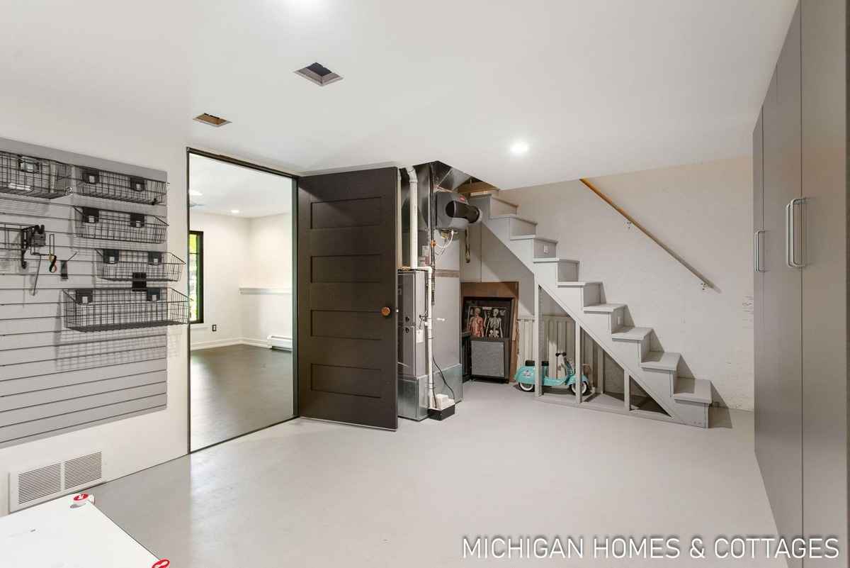 A basement area with a staircase, storage wall, and a dark door is shown.