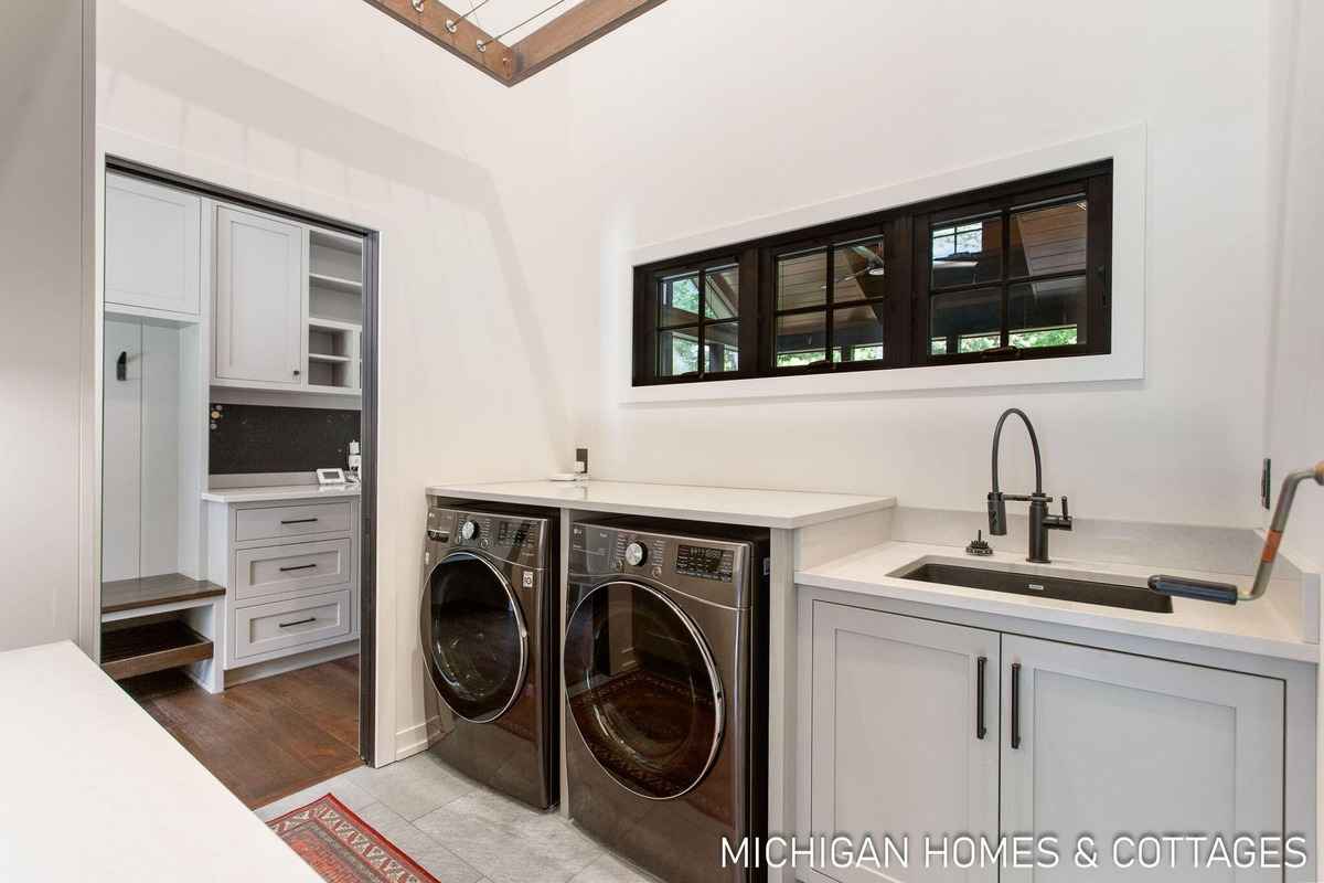 A laundry room with a washer and dryer, a sink, and a built-in storage area is shown.